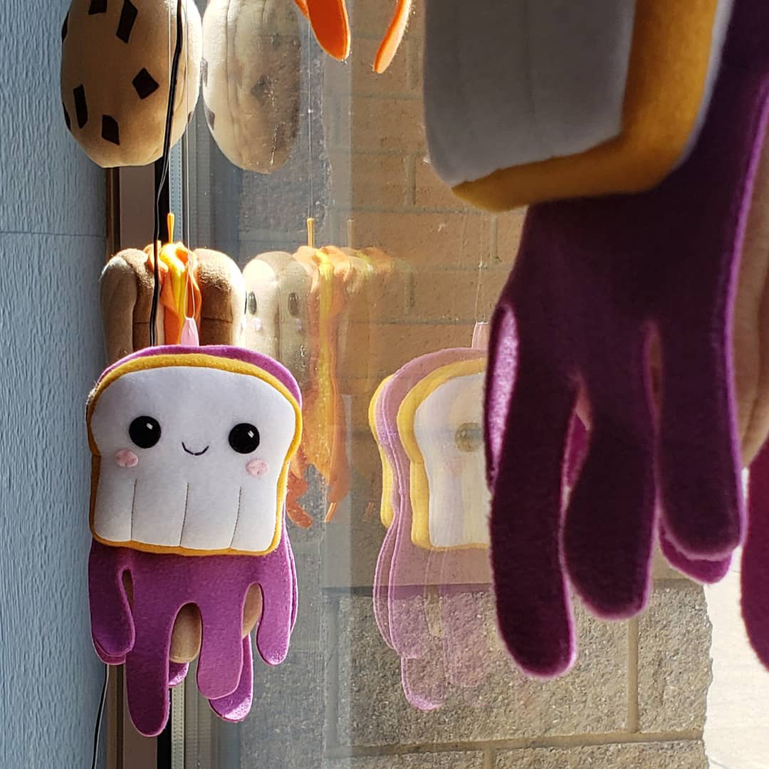 Silly sandwich and cookie plush art in a window installation by Sophia Adalaine at Matty J's Bakery and Cafe