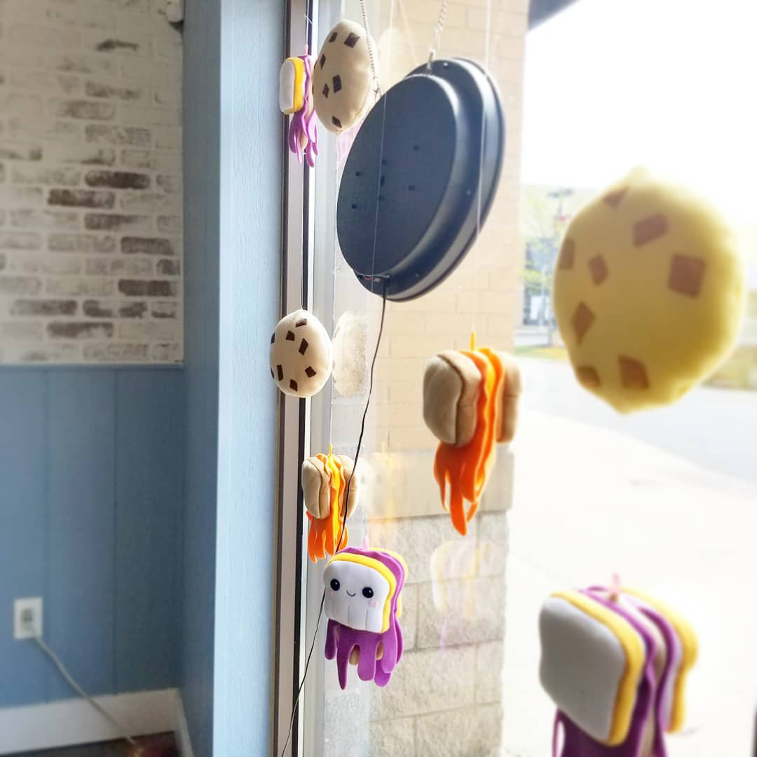Silly sandwich and cookie plush art in a window installation by Sophia Adalaine at Matty J's Bakery and Cafe
