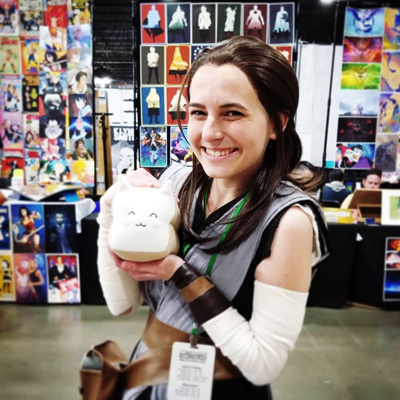 girl smiling with Meow-Bao the Catloaf plush toy at Motor City Comic Con