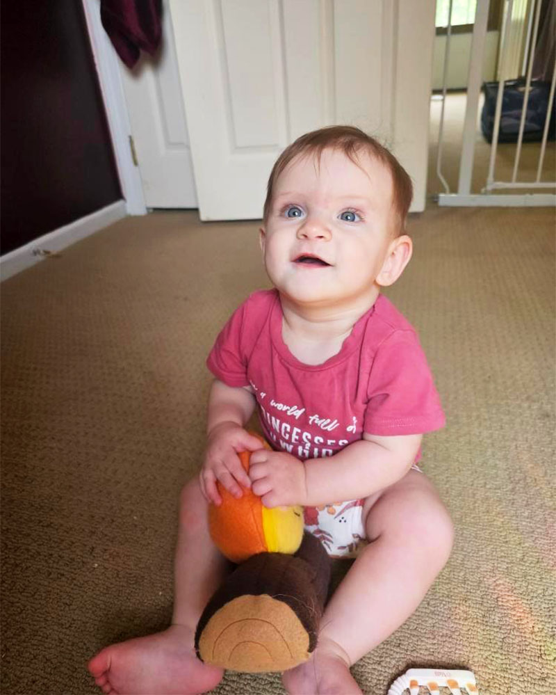 baby looking up with Happy Campfire plush toy